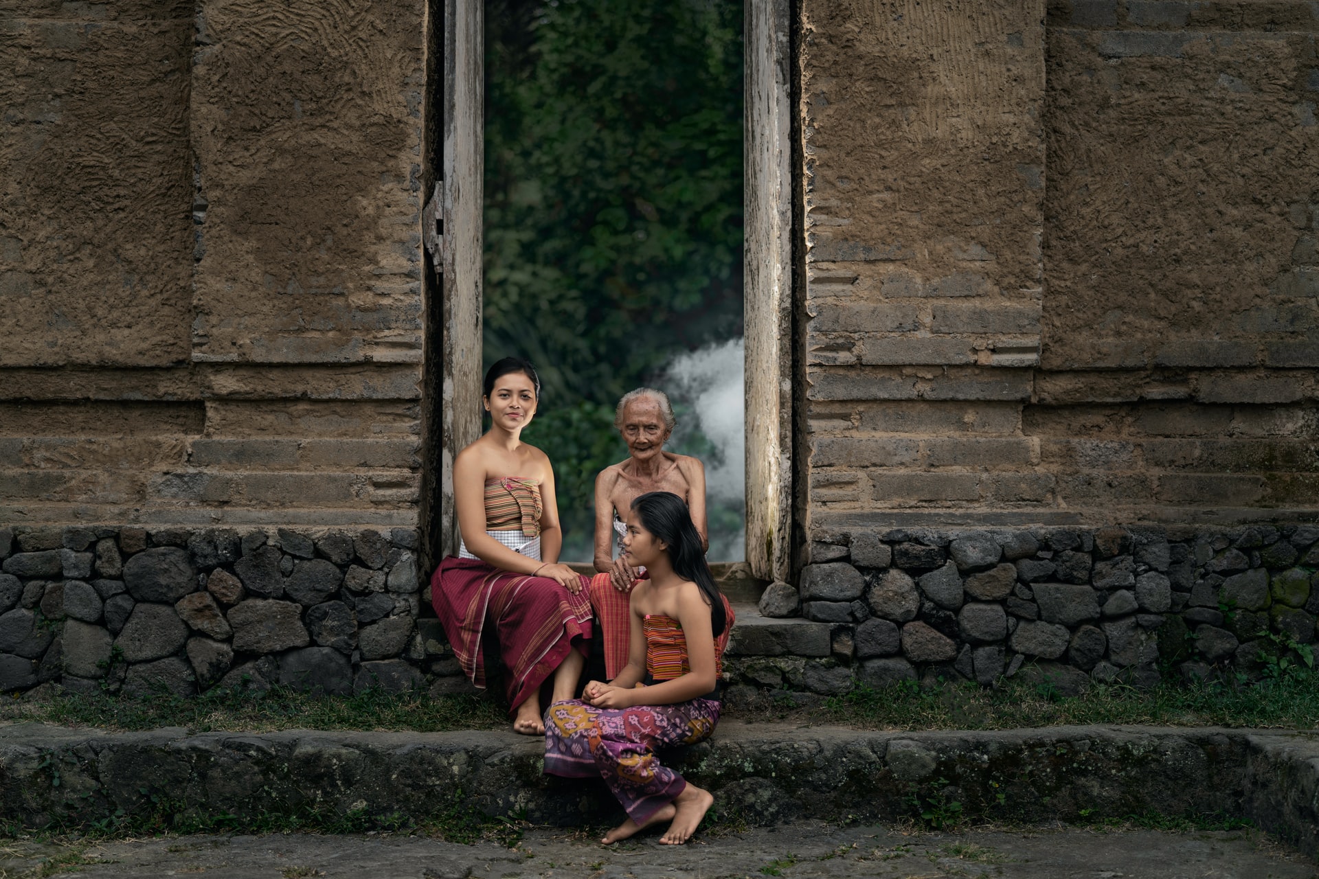 Three Balinese Women in traditional customs sitting in front of a door - Hotel Sidemen - Villa Uma Dewi Sri